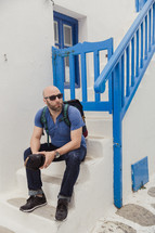 man sitting on steps and blue railing 