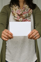 a woman holding up a blank envelope