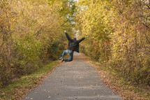a man walking on a paved path in fall celebrating 