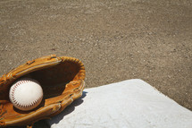 a softball and glove on a base 
