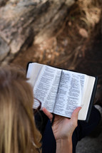 A woman sitting outside reading the Bible.