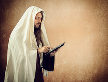 Jesus Christ reads the Holy Bible with the tablet