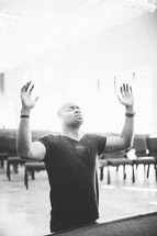 man with his hands raised in praise and worship to God in a church