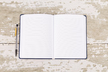 pencil and notebook on a white wood background 