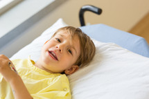 a boy child in a hospital gown lying in a hospital bed 