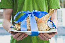 Turkey being served on a platter with a blue bow tied around it.