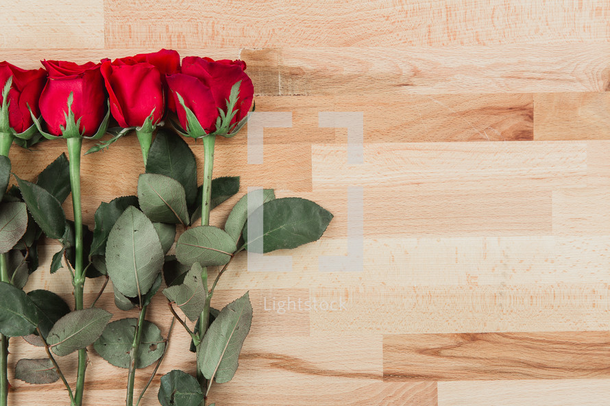 red long stem roses on wood