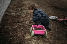 boy playing in dirt in the backyard 
