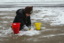 a child playing with snow in a driveway 