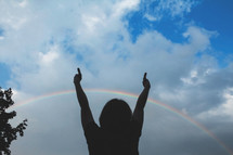 silhouette of a child under a rainbow 