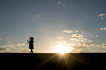 silhouette of a girl in a dress and sunburst 