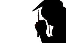 silhouette of a graduate with head bowed and praying hands 
