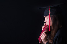female graduate holding a Bible and praying 