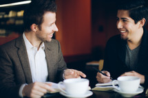 two men smiling and talking over coffee during a Bible study