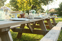 Place settings on picnic tables outside.