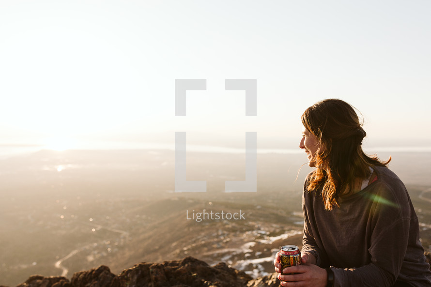 Woman holding a beer while on a sunset hike