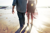 husband and wife walking hand in hand on a beach 