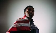 An African American man wrapped in an American flag 