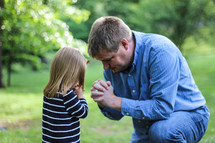 Father praying with his daughter outside.