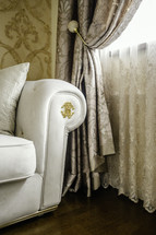 Ornate curtains next to chair with monogram