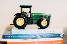 green tractor figurine on a stack of books 