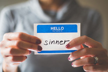 man holding a name tag with the word sinner 