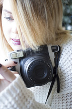 a woman in a sweater holding a camera 