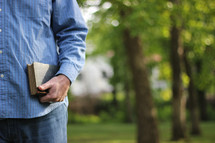 Man standing outside holding a Bible.