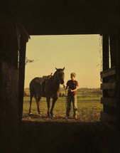 Teen boy bringing horse to stall