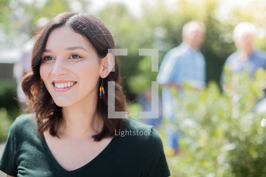 headshot of a young woman and friends talking at a backyard summer party