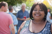 headshot of a woman and friends standing around talking at a backyard summer party
