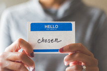 woman holding a name tag with the word chosen 