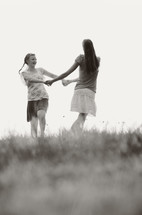 Girls holding hands playing in a field