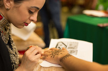a woman painting henna tattoos 