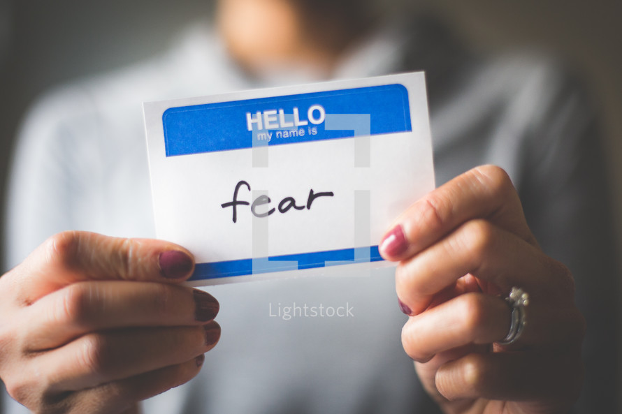 woman holding a name tag with the word fear 