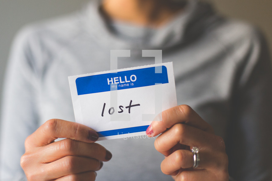 woman holding a name tag with the word lost 
