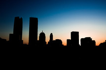 silhouettes of buildings in a city at sunset  