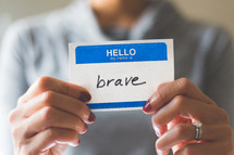 woman holding a name tag with the word brave 