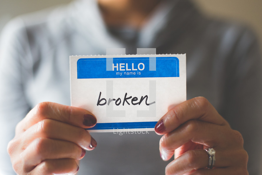 woman holding a name tag with the word broken 