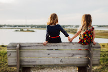 sisters holding hands on a park bench 