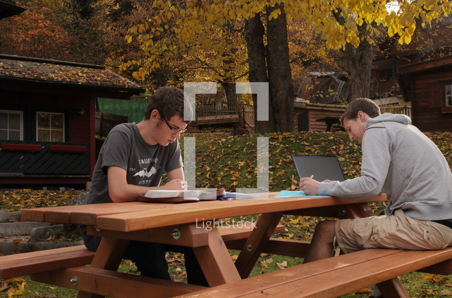 men studying at a picnic table 