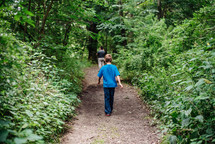 father and kids walking on a path in the woods 