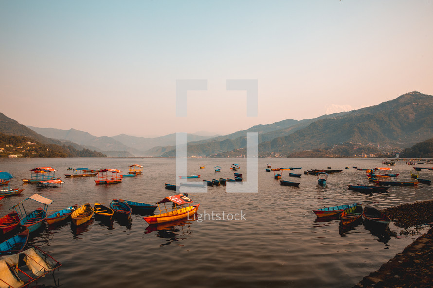 boats and mountains on a lake in Pokhara Nepal at sunset