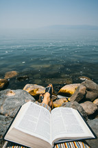 feet and Bible at the shores of the sea of Galilee 