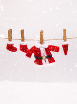 Santa suit and Christmas stockings on a clothesline in the snow 