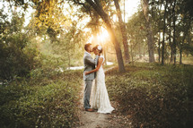 groom kissing his bride on the forehead standing on an outdoor path