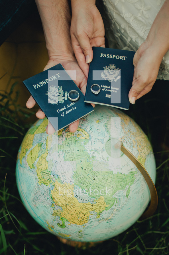 couple with wedding bands on passports and a globe 