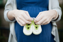 a pregnant mother holding knitted booties 