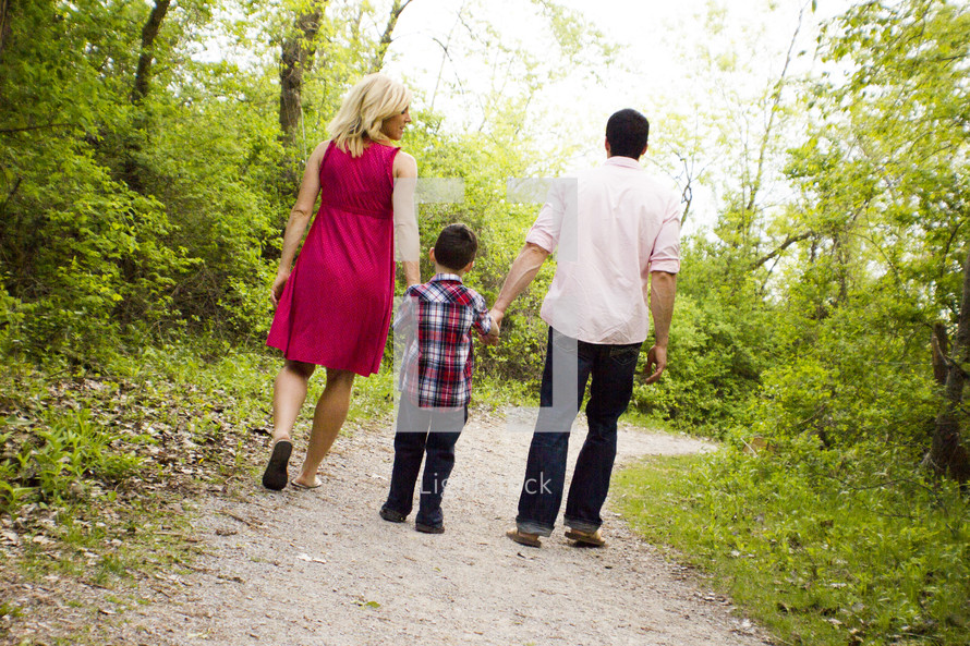 Back view of mother, father and son walking dow a wooded path