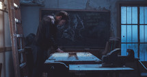 a man in a workshop and words on a chalkboard 